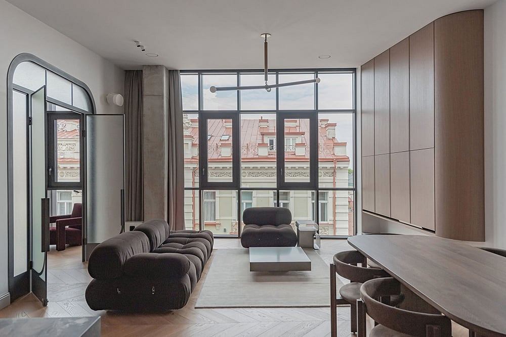 Spacious modern living room with large windows, sophisticated furnishings, and sleek cabinetry.