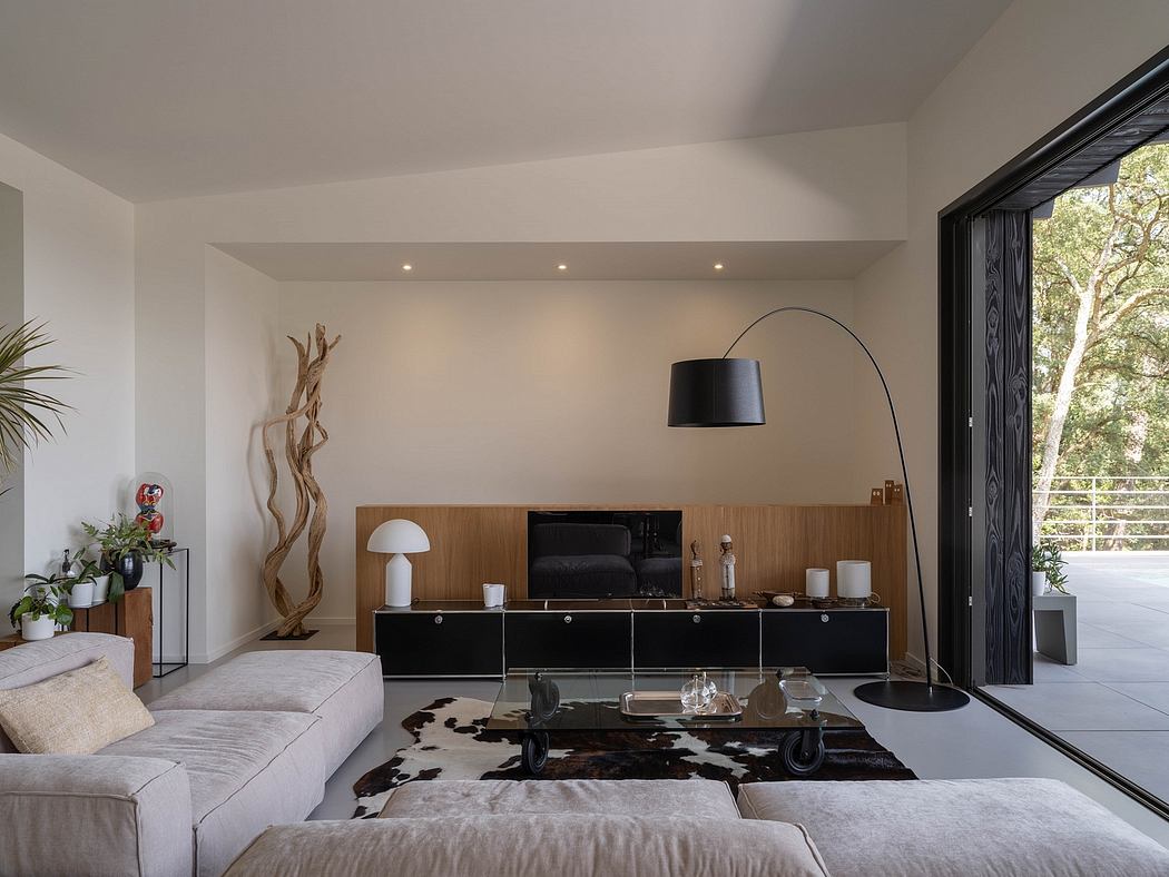 Spacious, airy living room with minimalist furniture, wooden accents, and large window overlooking nature.