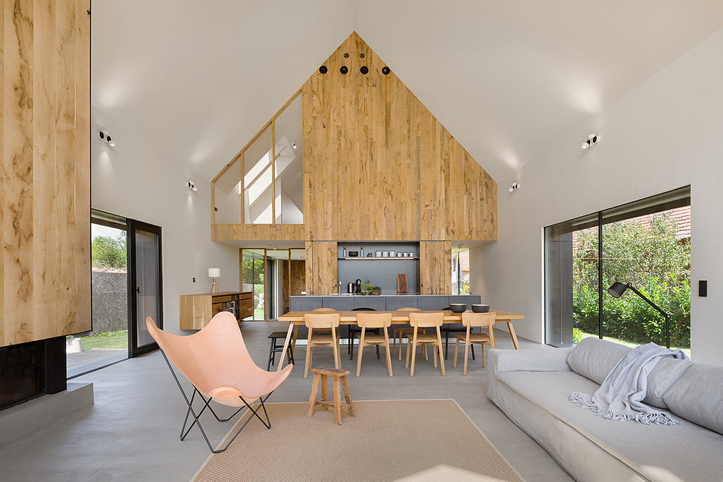 A modern, open-concept interior with a vaulted wood ceiling, dining area, and minimalist furnishings.