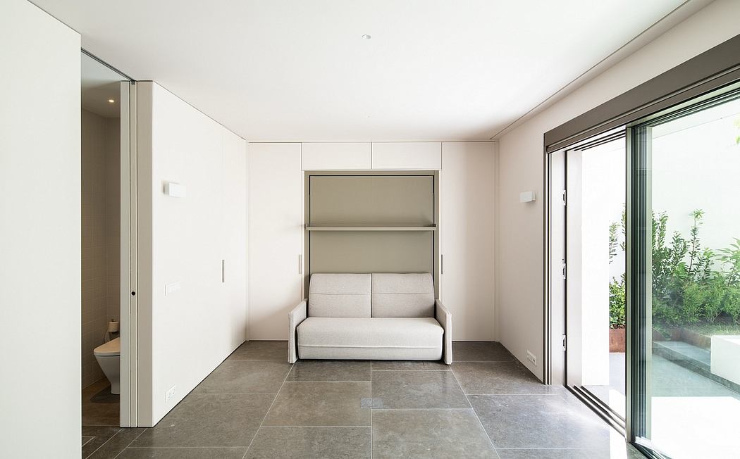 Minimalist living room with built-in sofa bed, floor-to-ceiling windows, and tiled flooring.