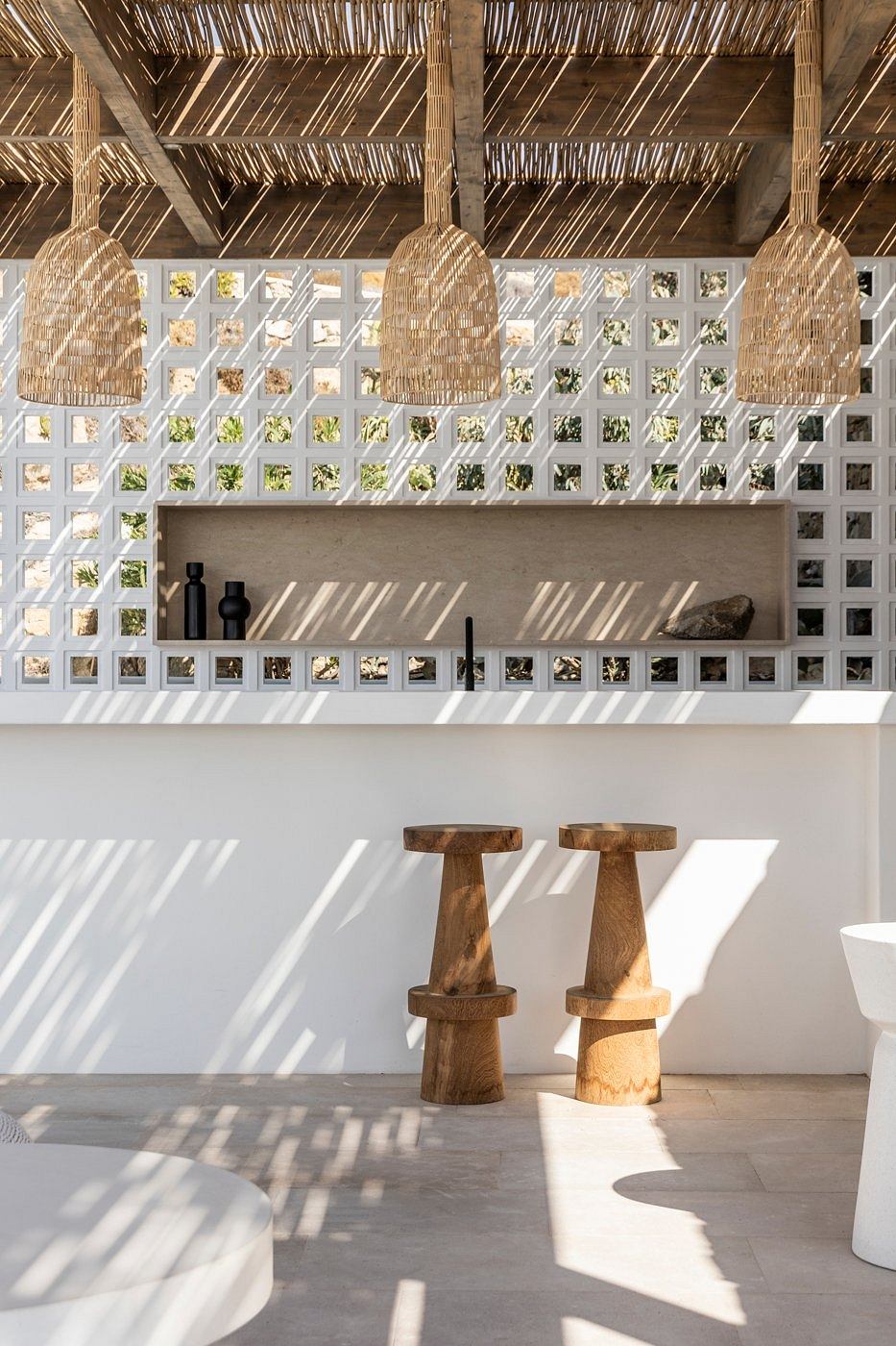 Minimalist interior with natural textures, geometric shelving, and layered lighting.