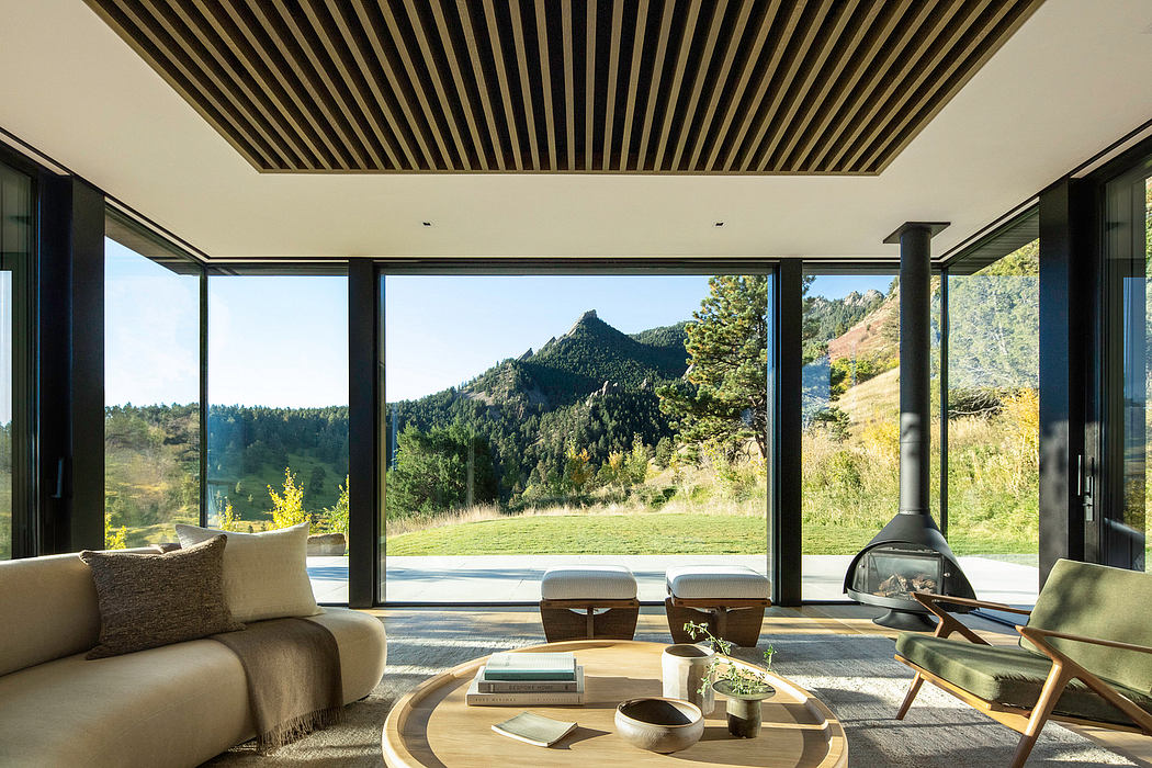 Large windows provide panoramic mountain views, while a modern ceiling and furnishings create a harmonious interior design.