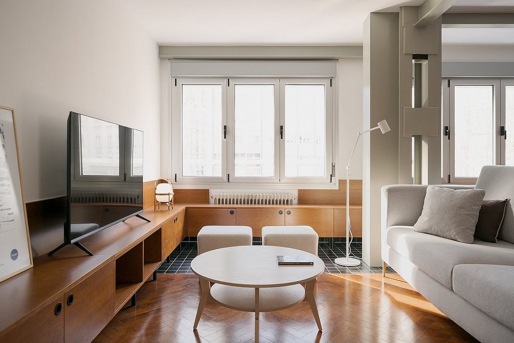 Minimalist living room with large windows, wooden furniture, and a circular coffee table.