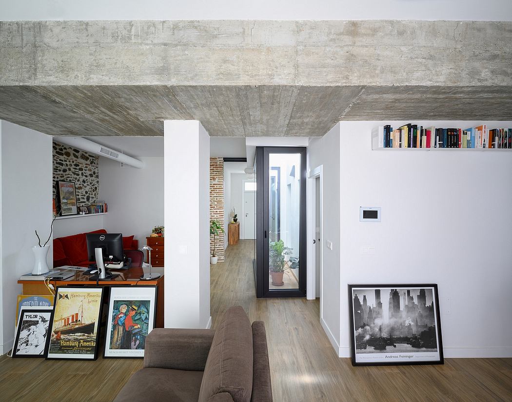 A spacious modern loft with an exposed concrete ceiling, brick walls, and wooden flooring.