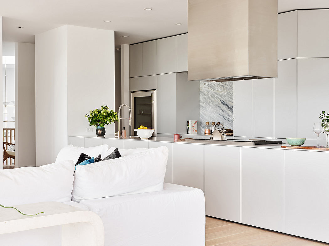 A modern kitchen with sleek cabinetry, marble countertops, and a cozy living area.