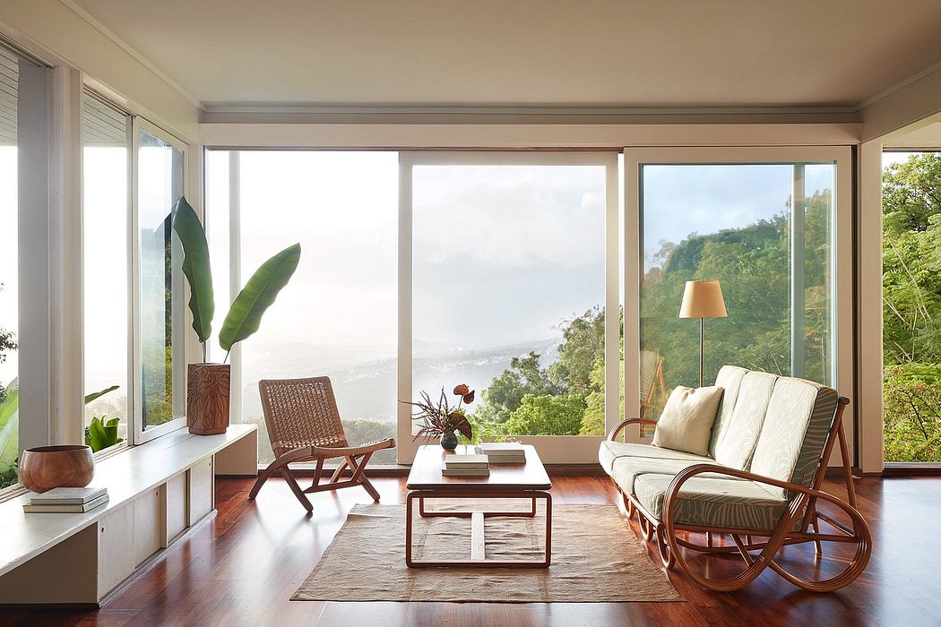 Bright, modern living room with large windows showcasing lush greenery outside.