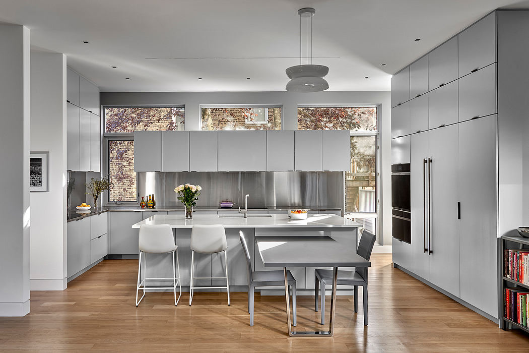 Sleek, minimalist kitchen design with stainless steel appliances, a central island, and large windows.