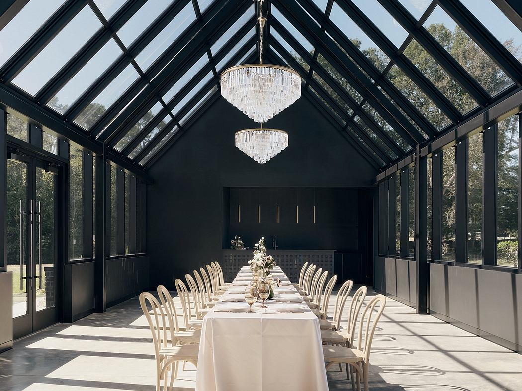 A spacious, contemporary dining room with a dramatic glass roof, sleek black walls, and ornate chandeliers.