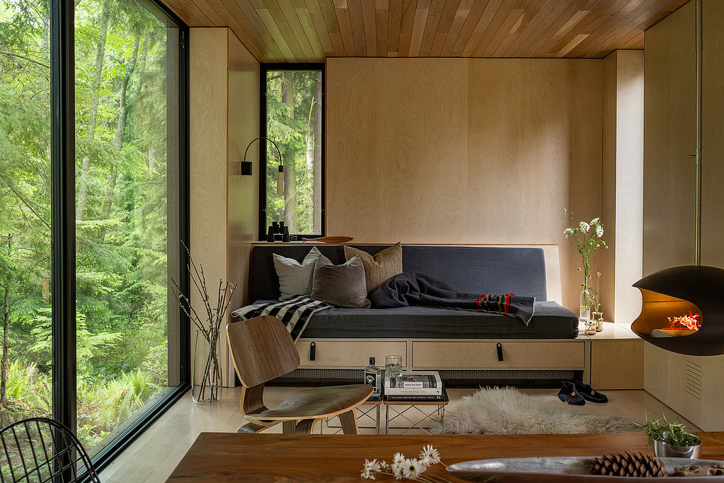Cozy modern cabin interior with wooden walls, platform bed, and large windows overlooking nature.