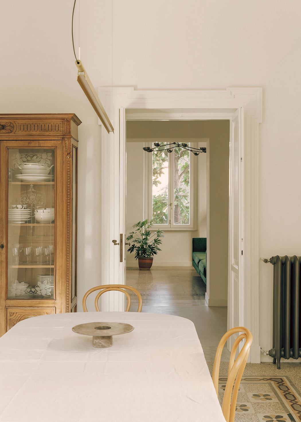 A warm, inviting dining space with a wooden cabinet, marble-topped table, and pendant lighting.