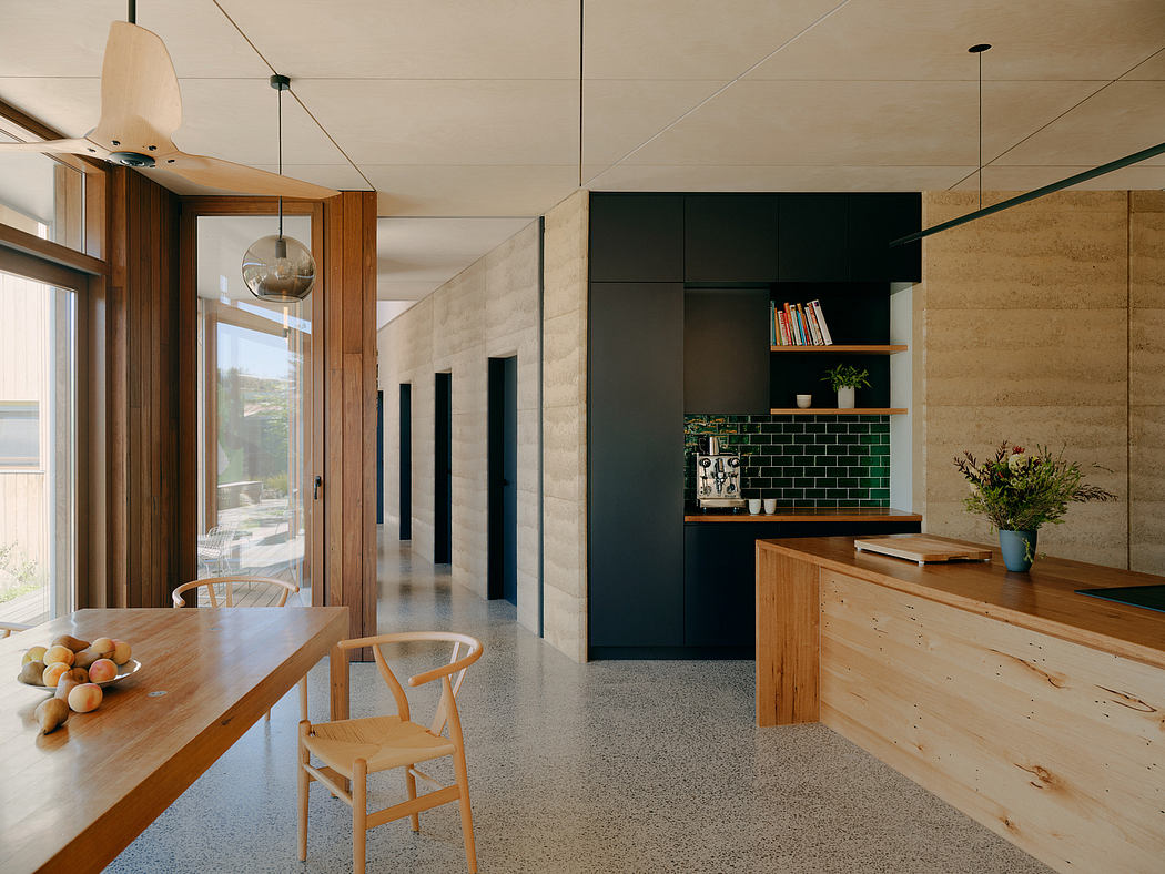 A modern, minimalist kitchen with exposed concrete walls, wooden furniture, and a green tile backsplash.