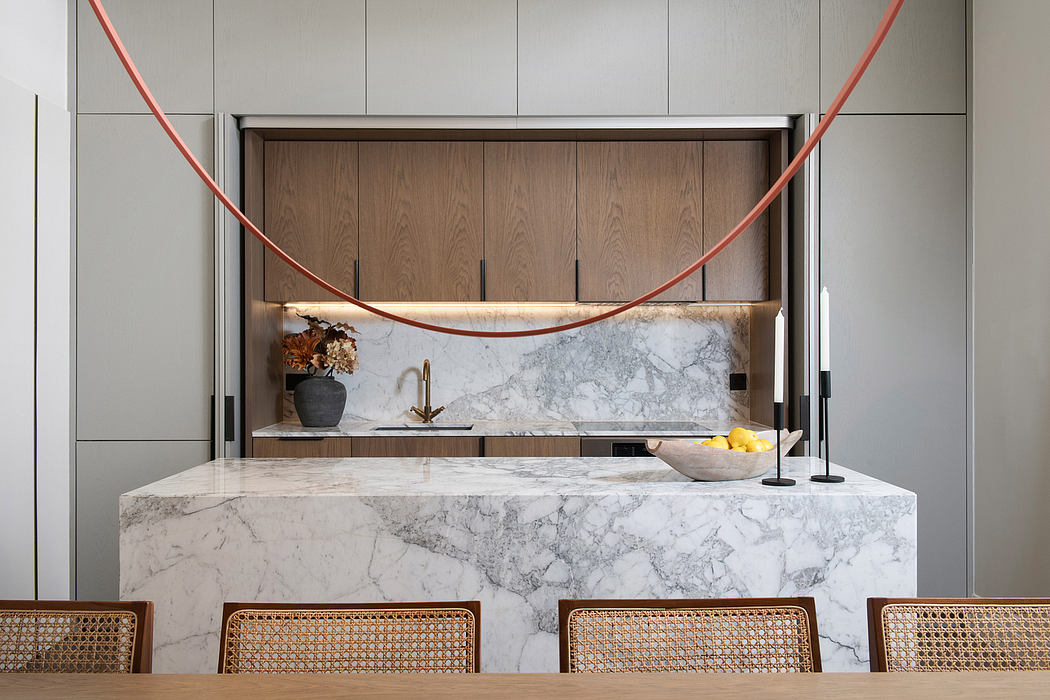 Modern kitchen with sleek marble countertop, wooden cabinets, and bold red lighting fixture.