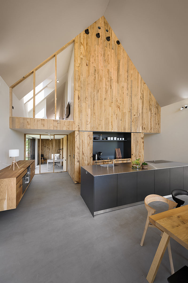 A modern kitchen design featuring a wooden accent wall and sleek black cabinetry.
