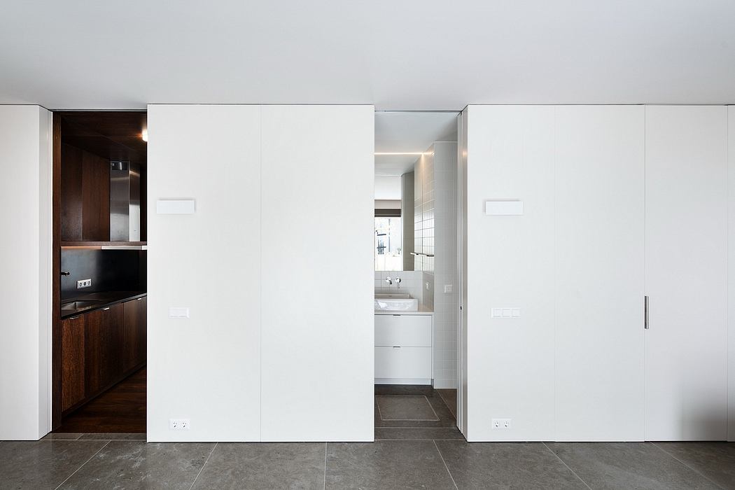 Sleek, minimalist interior with dark wood cabinets, white walls, and tile flooring.