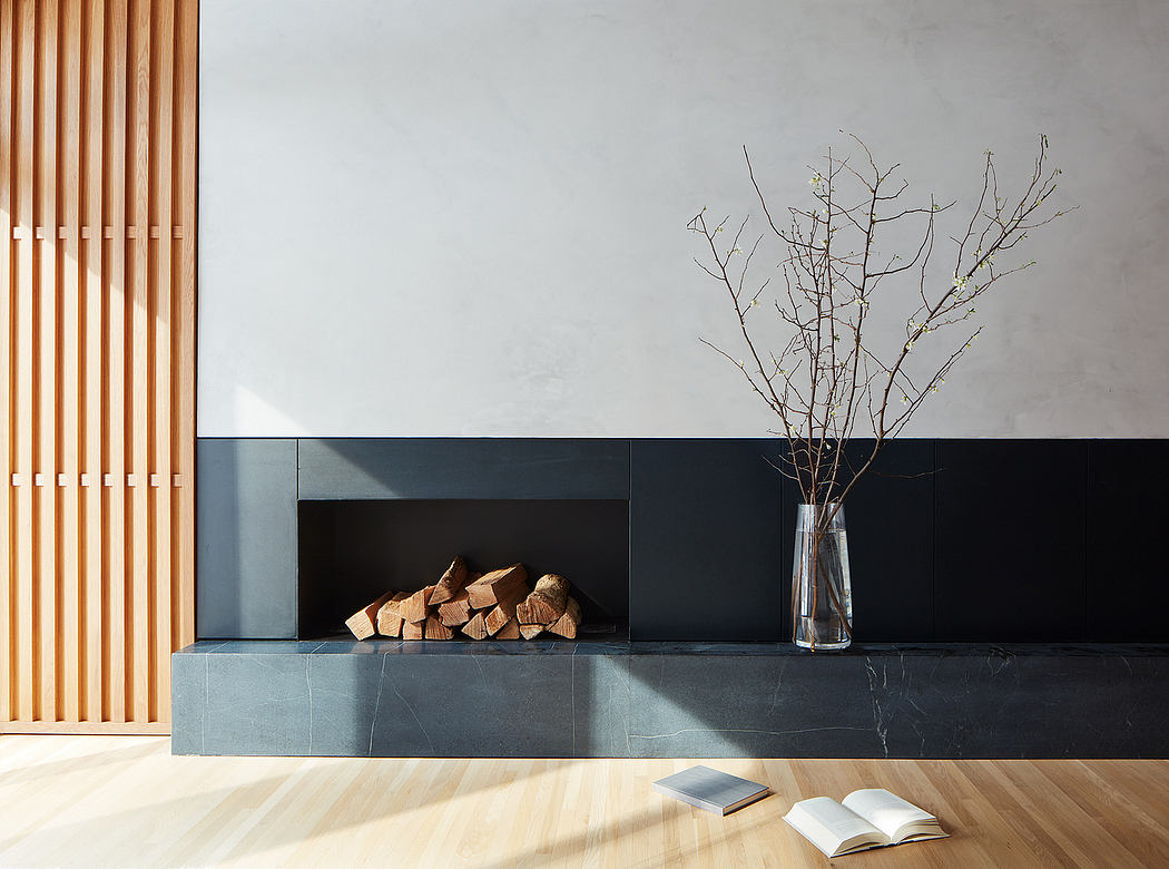 Modern minimalist interior with wooden blinds, black fireplace, and a vase with bare branches.