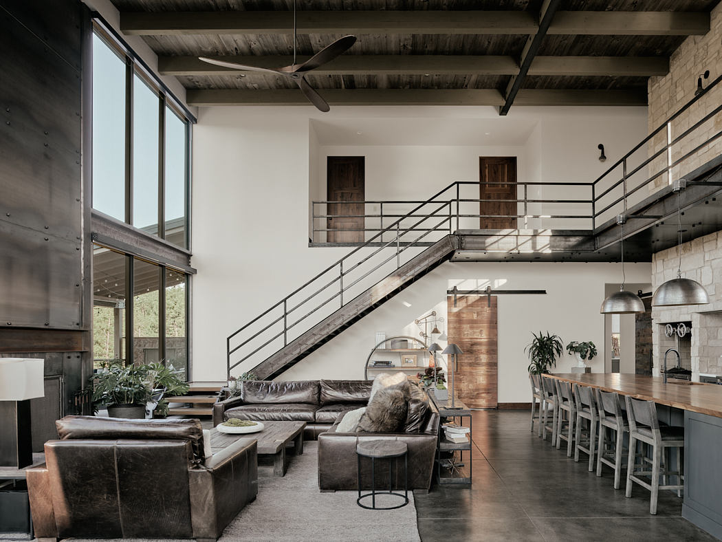 Spacious industrial-style living area with metal staircase, seating, and dining space.