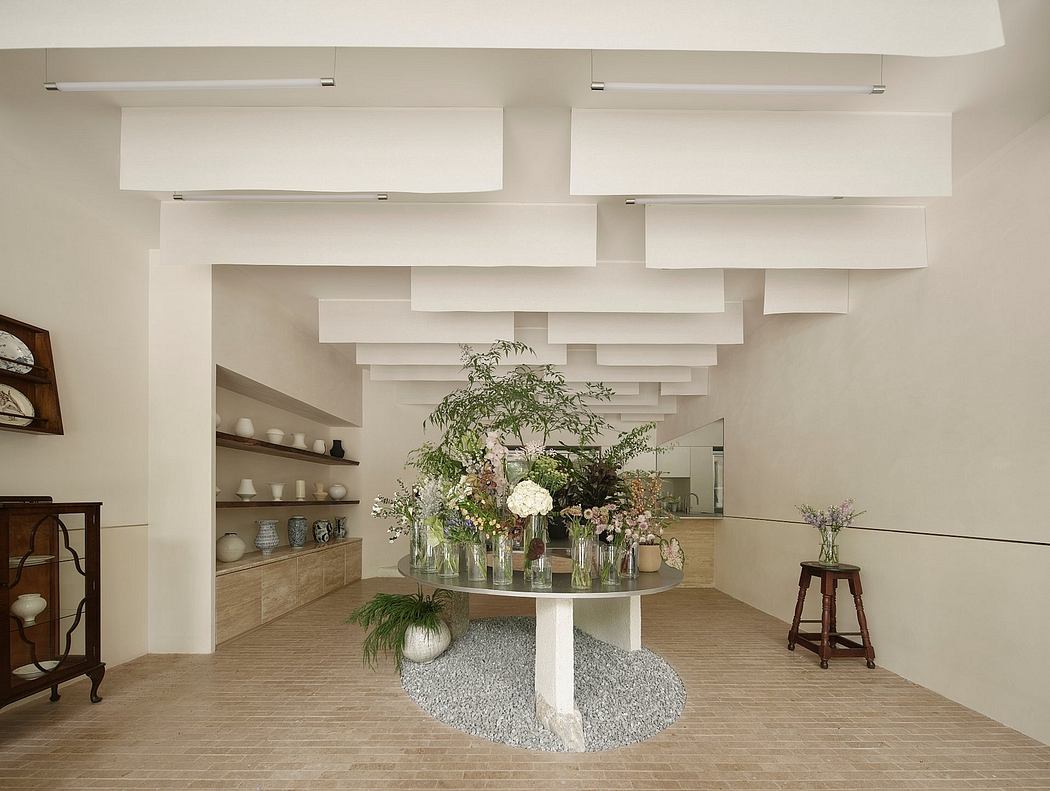 Minimalist architectural decor with elevated floral arrangement, shelves, and stool.