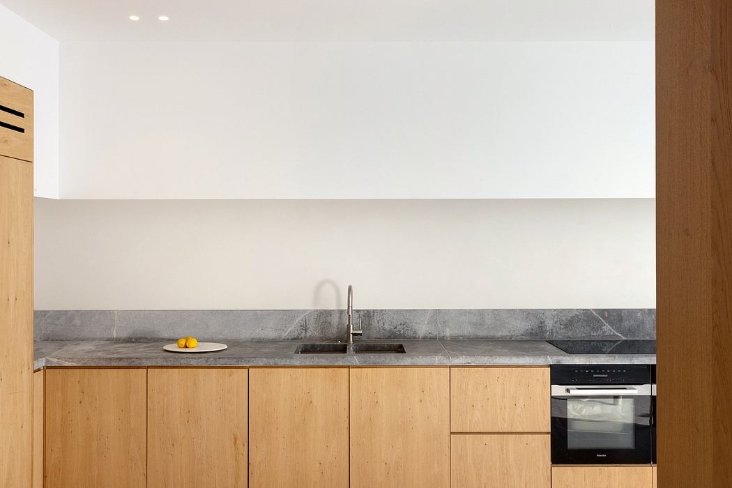 Minimalist kitchen with wood cabinets, stone countertop, and a sink under the window.
