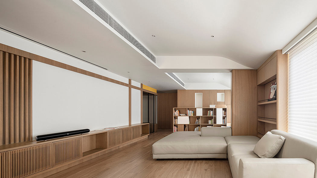 Spacious, minimalist living room with wooden accents, built-in shelving, and a large sofa.