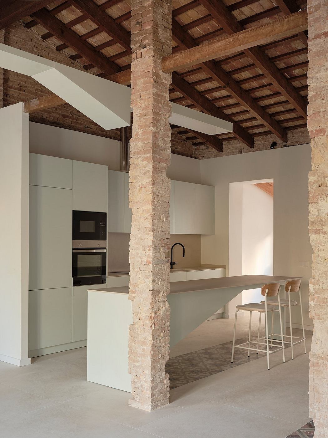 A modern kitchen with exposed brick walls, wooden beams, and minimalist cabinetry.