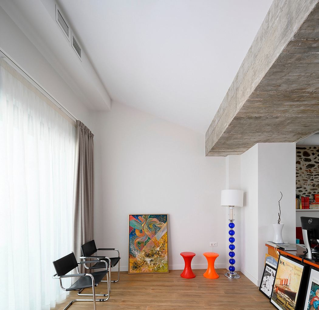 Minimalist room with exposed concrete beams, colorful accents, and modern furnishings.
