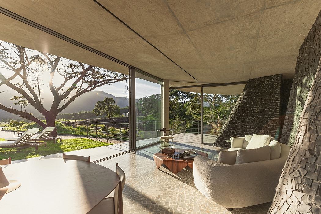 Spacious open-plan living area with panoramic views, stone wall, and modern furniture.