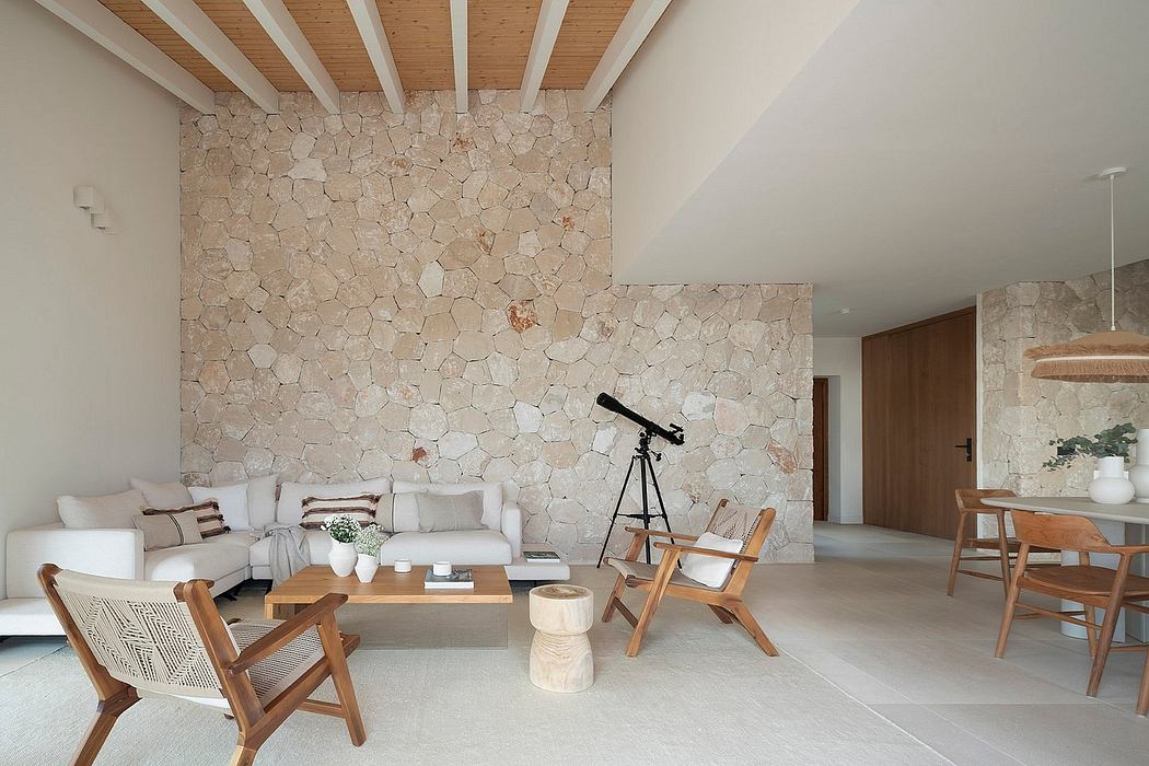 A spacious, modern living space with a stone accent wall, wooden ceiling beams, and minimalist furniture.