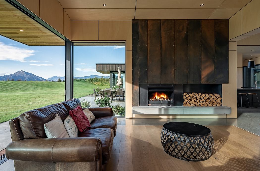 A modern living room with a large fireplace, wooden paneling, and expansive views of the landscape.