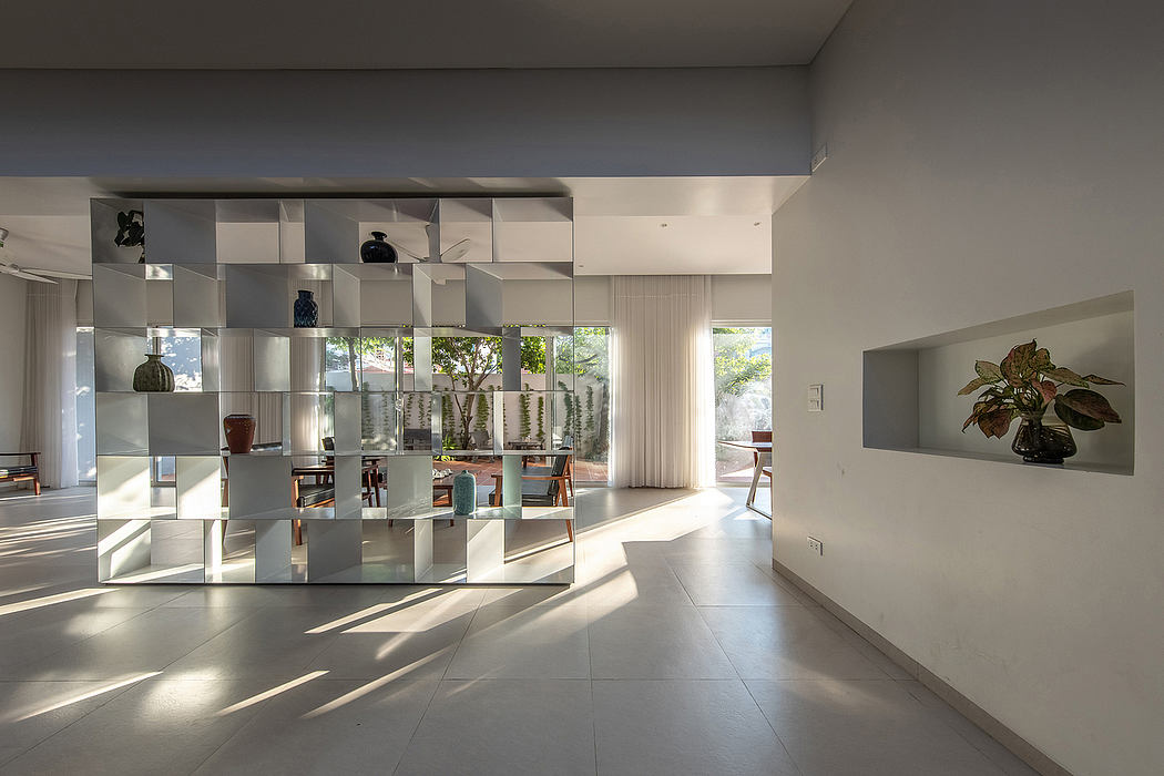 Modern, open-plan living space with floor-to-ceiling glass walls, sleek shelving, and lush plants.