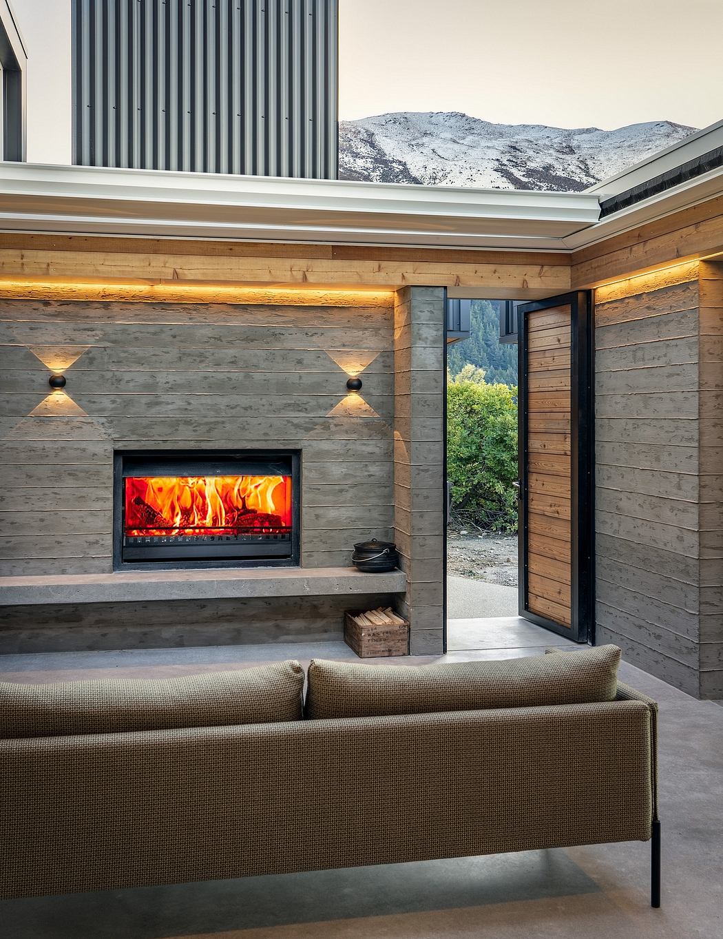 Cozy cabin interior with a stone fireplace, wooden walls, and a panoramic mountain view.