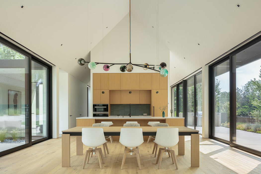 Bright, modern kitchen with a large dining table, glass walls, and a unique light fixture.