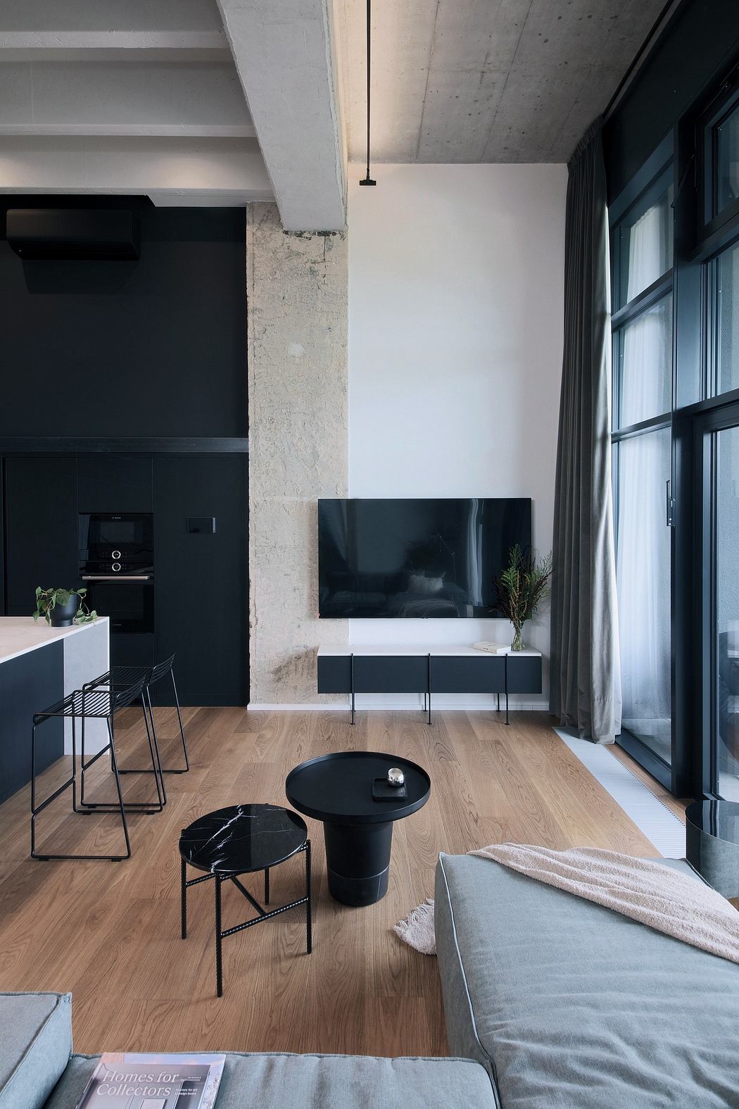 Minimalist living room with concrete walls, wooden flooring, and a sleek TV console.