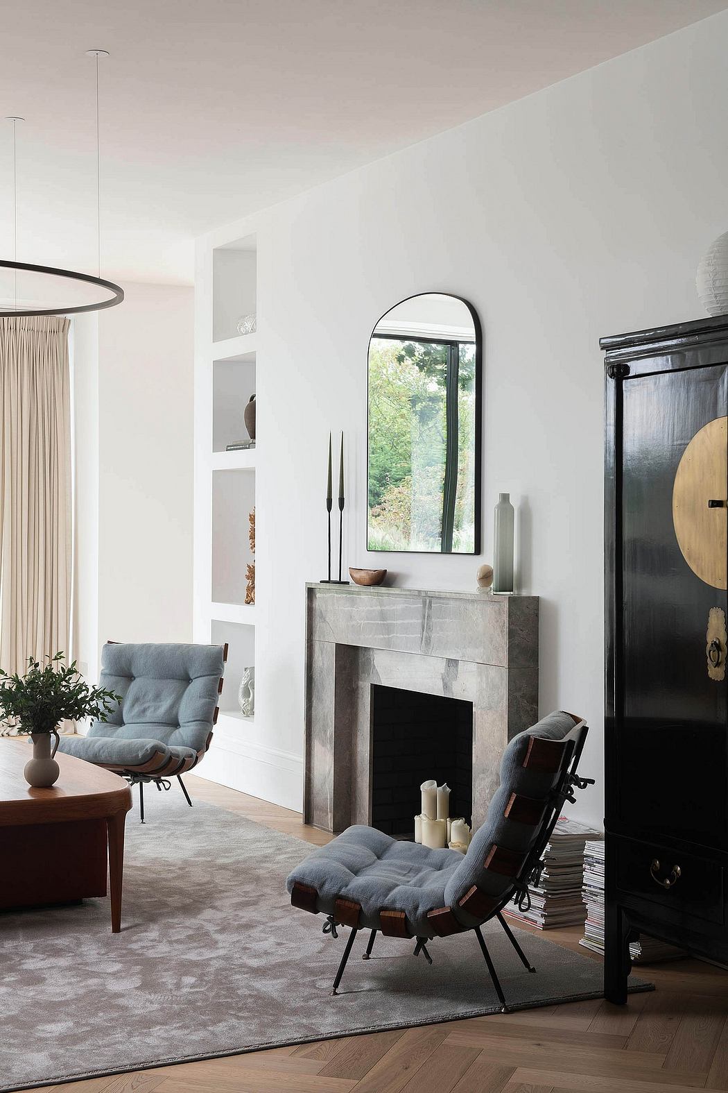 Elegant living room with arched window, marble fireplace, and plush gray seating.