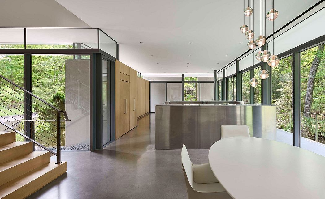 Modern, open-plan interior with floor-to-ceiling windows, sleek kitchen island, and sculptural lighting.