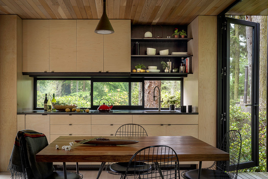 Rustic, wood-paneled kitchen with large windows, open shelving, and a dining table.