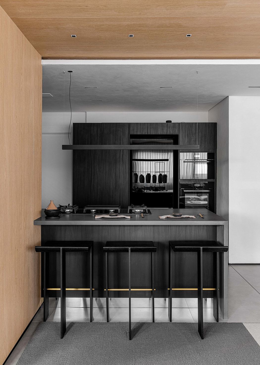 Modern kitchen with sleek black cabinetry, bar seating, and recessed lighting.