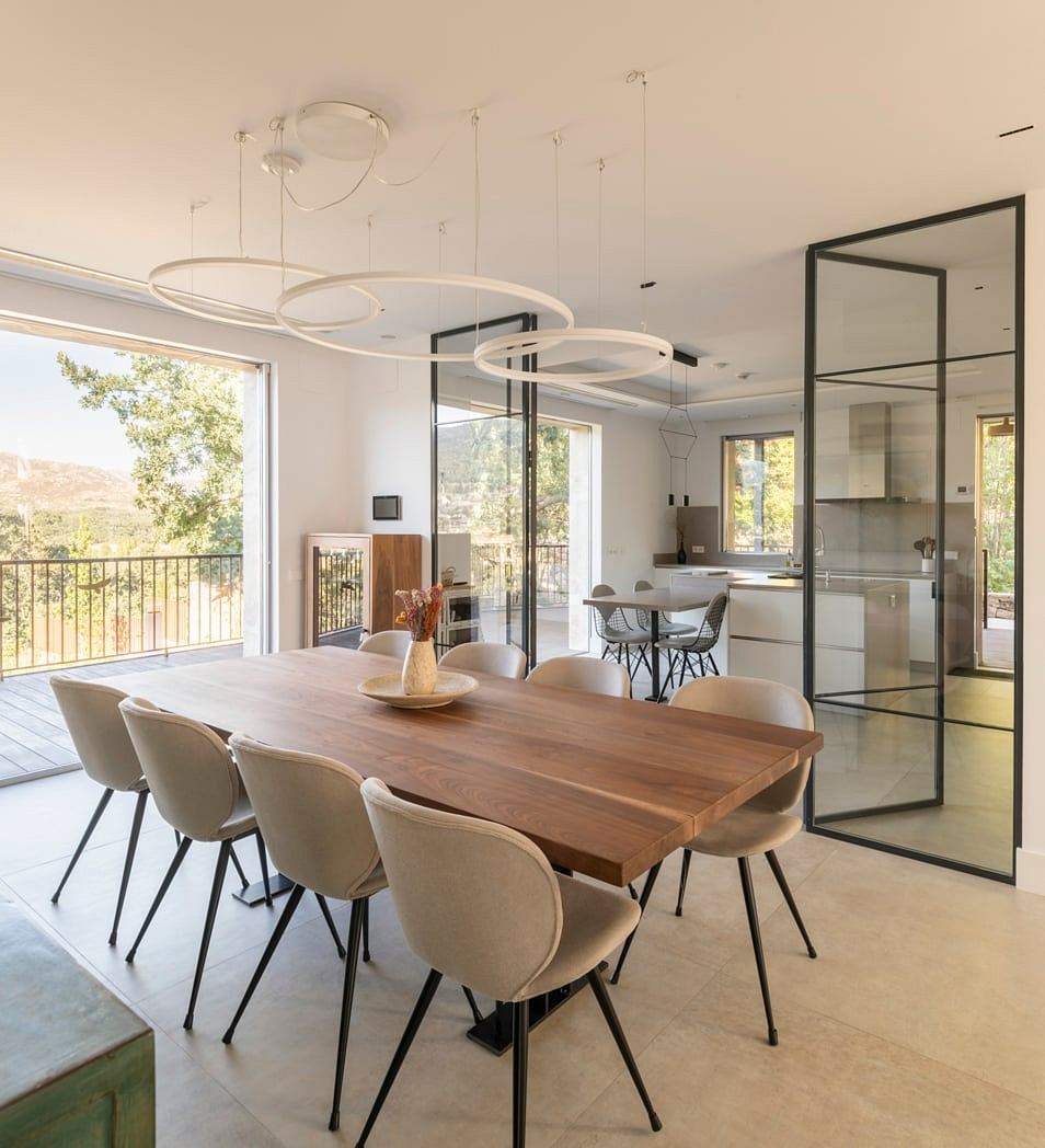 Spacious modern dining room with wooden table, pendant lighting, and glass walls.