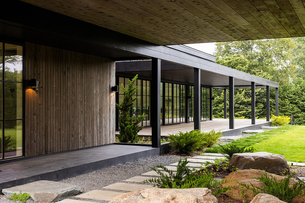 Rustic wooden exterior with large glass windows and a covered porch overlooking lush greenery.