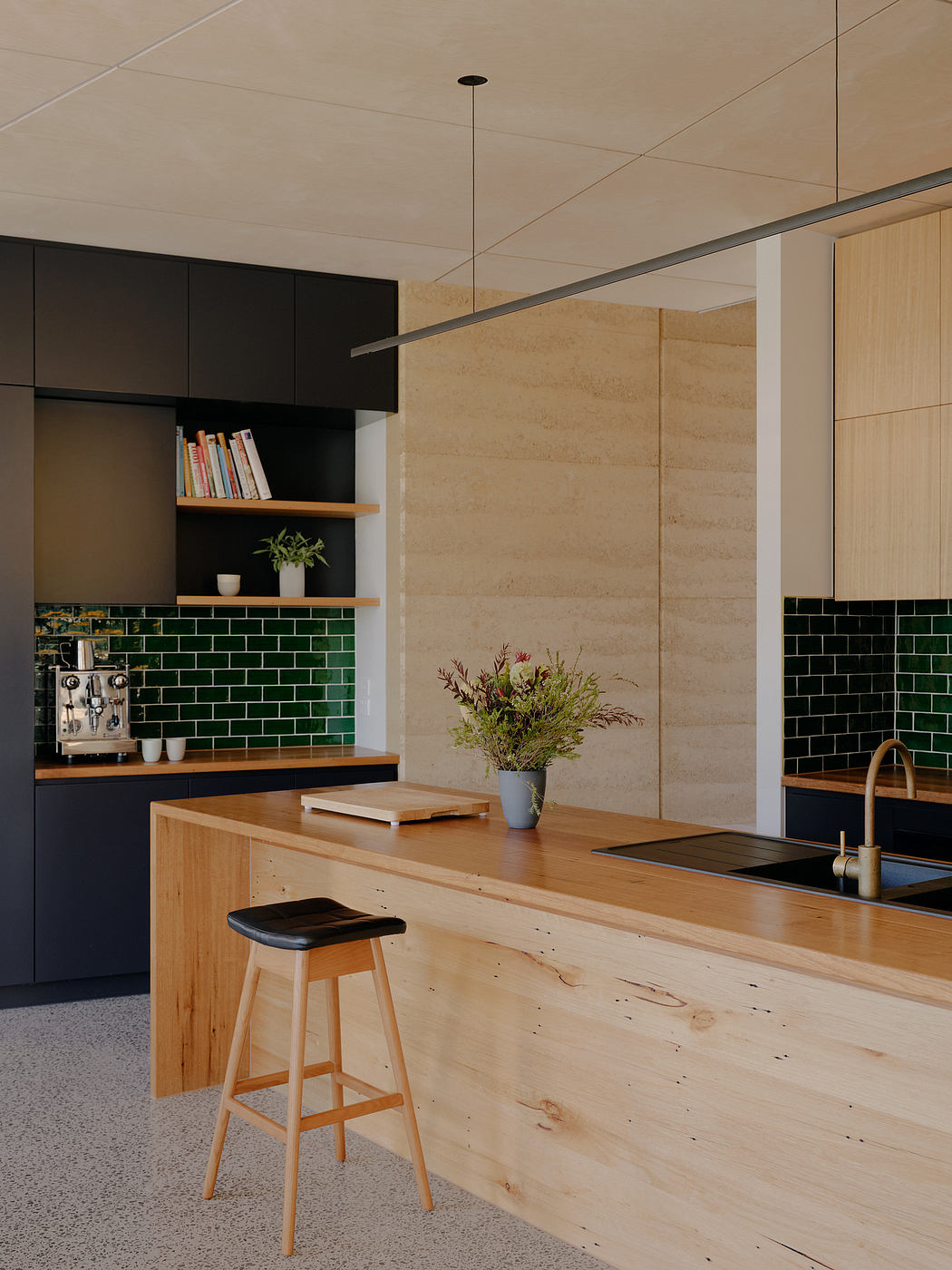 Modern kitchen with wooden counter, green subway tiles, and built-in shelving.