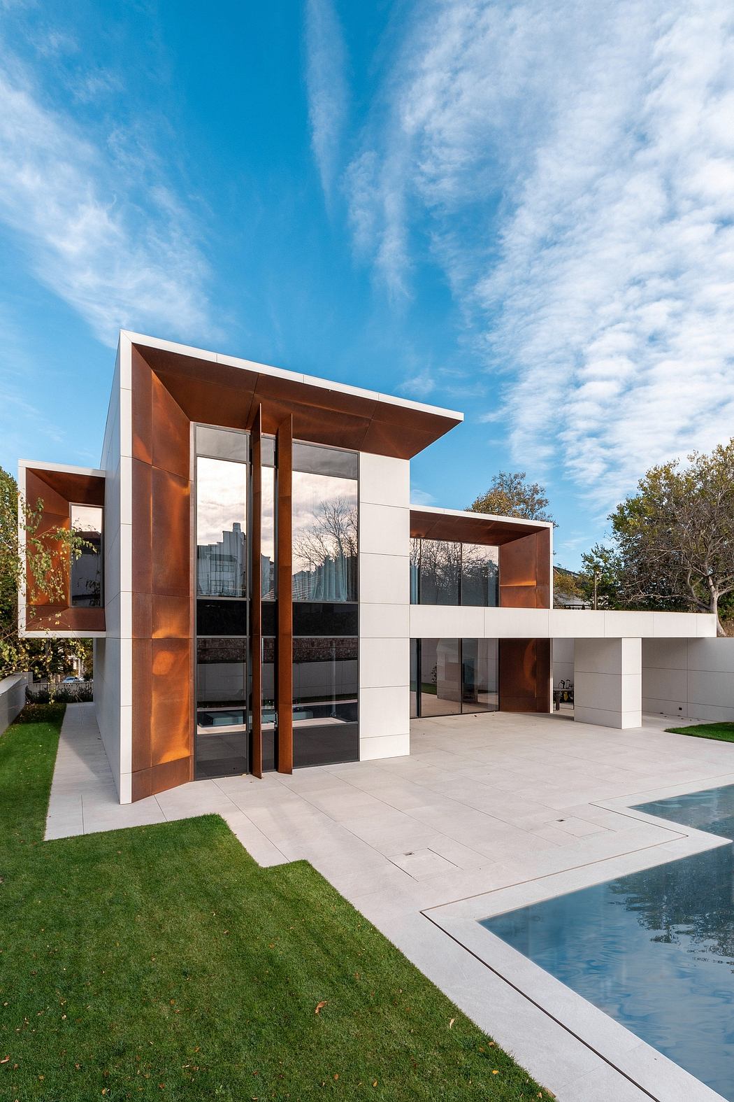Modern, minimalist exterior featuring geometric shapes, glass walls, and a pool.