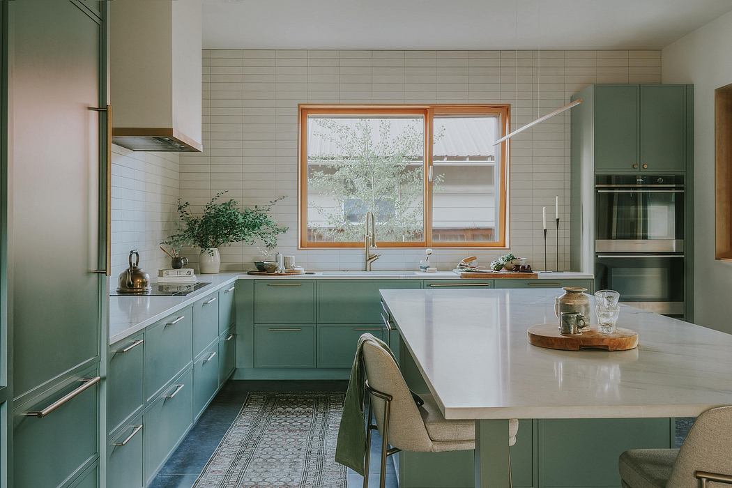 Bright, modern kitchen with green cabinetry, wood accents, and large window overlooking greenery.