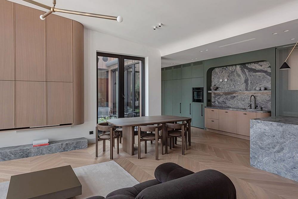 Sleek, modern kitchen and dining area with natural wood accents and grey stone finishes.