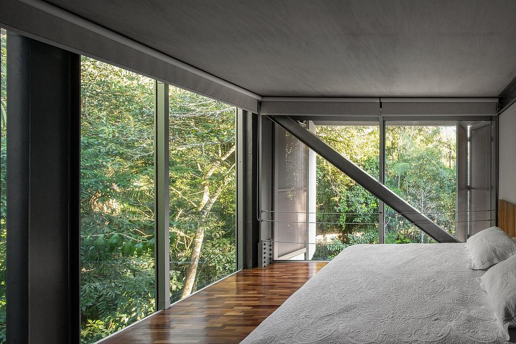 Minimalist bedroom with large glass windows overlooking lush greenery.