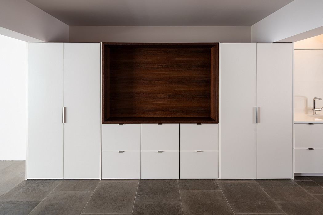 Modern built-in cabinetry with sleek white doors and a recessed wooden niche above.