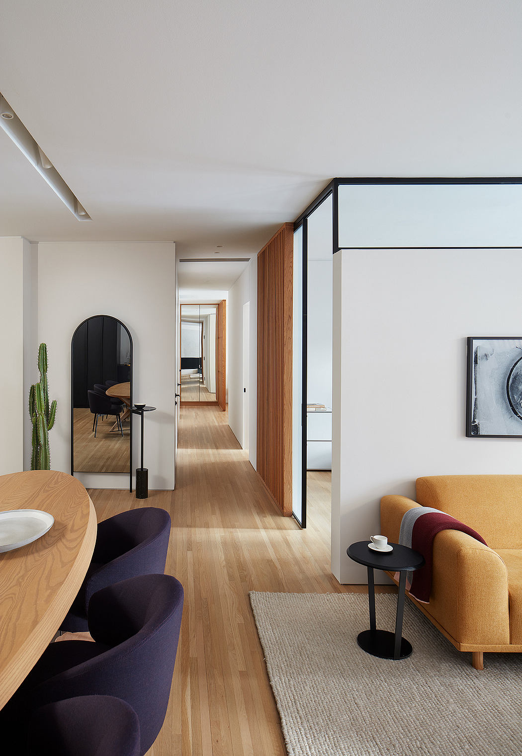 Stylish open-concept living space with modern furnishings, wood flooring, and black-framed glass walls.