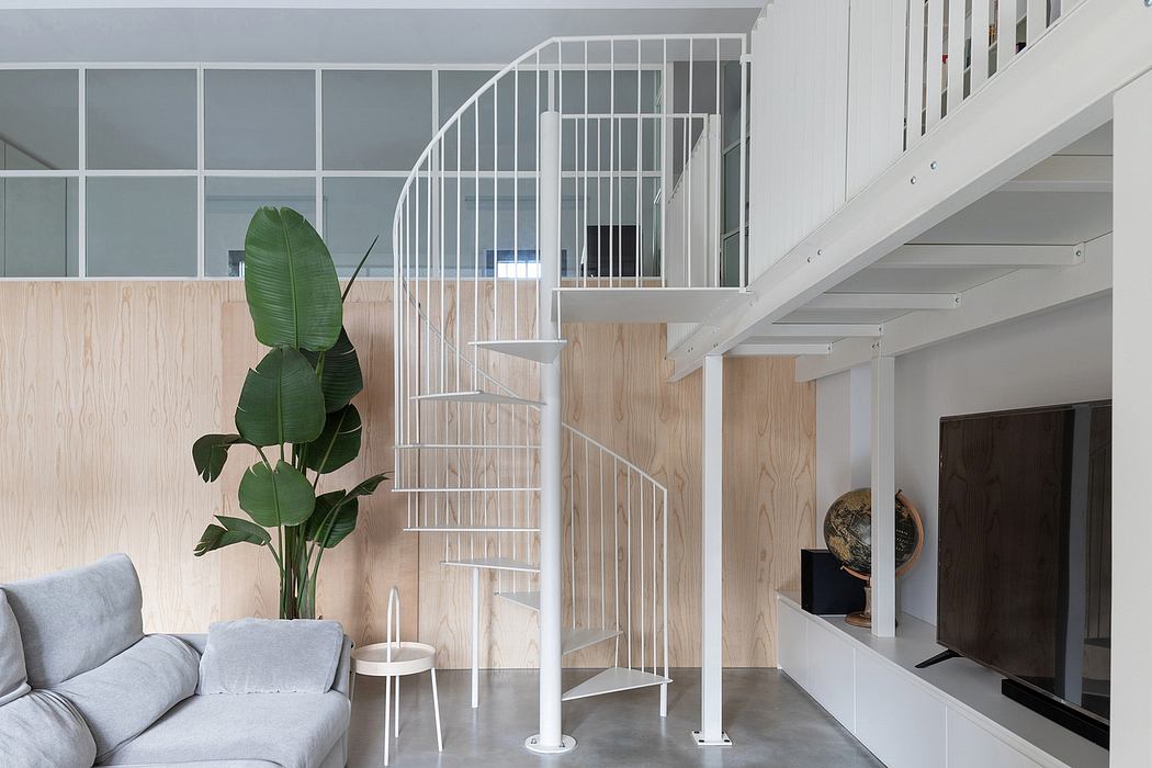 Spiral staircase, wooden paneling, and lush indoor plant in modern minimal interior.