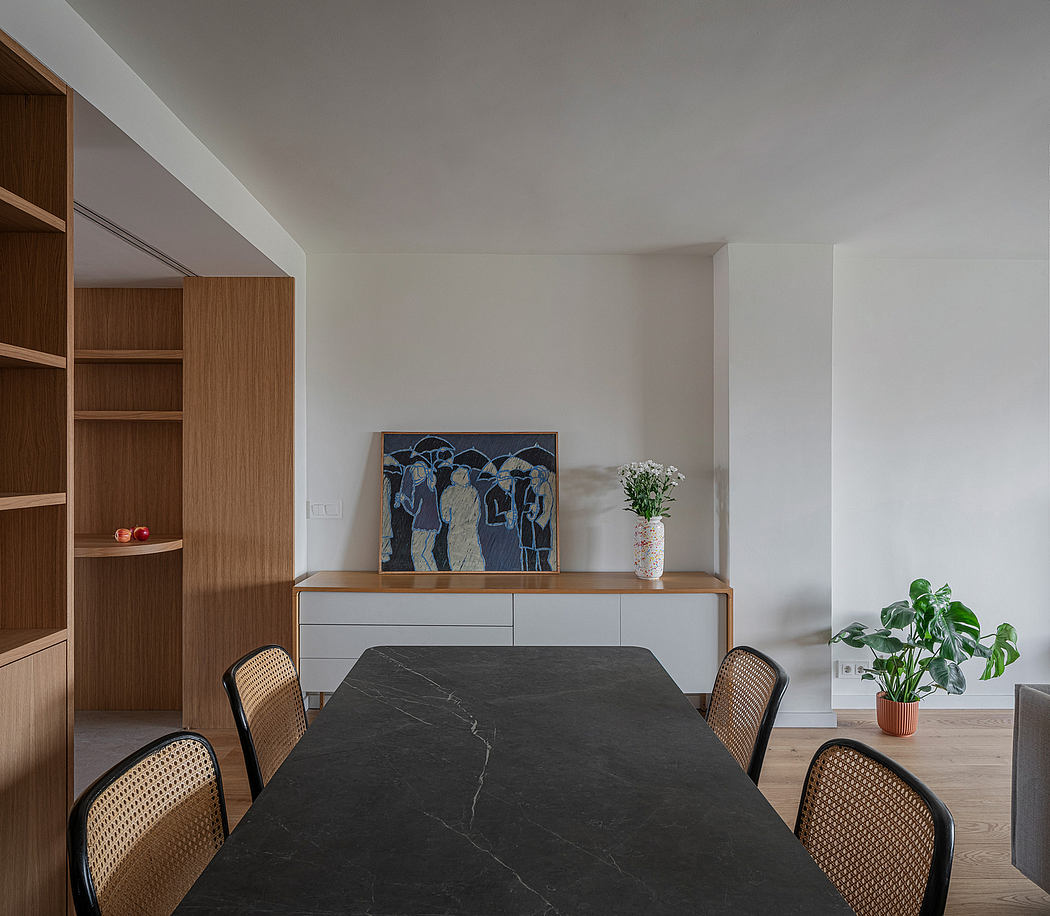 Minimalist dining area with wooden storage, marble table, and abstract art.