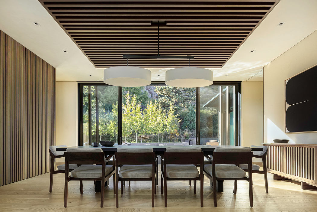 Sleek wooden ceiling beams, large windows, and a modern dining table create a warm, inviting space.