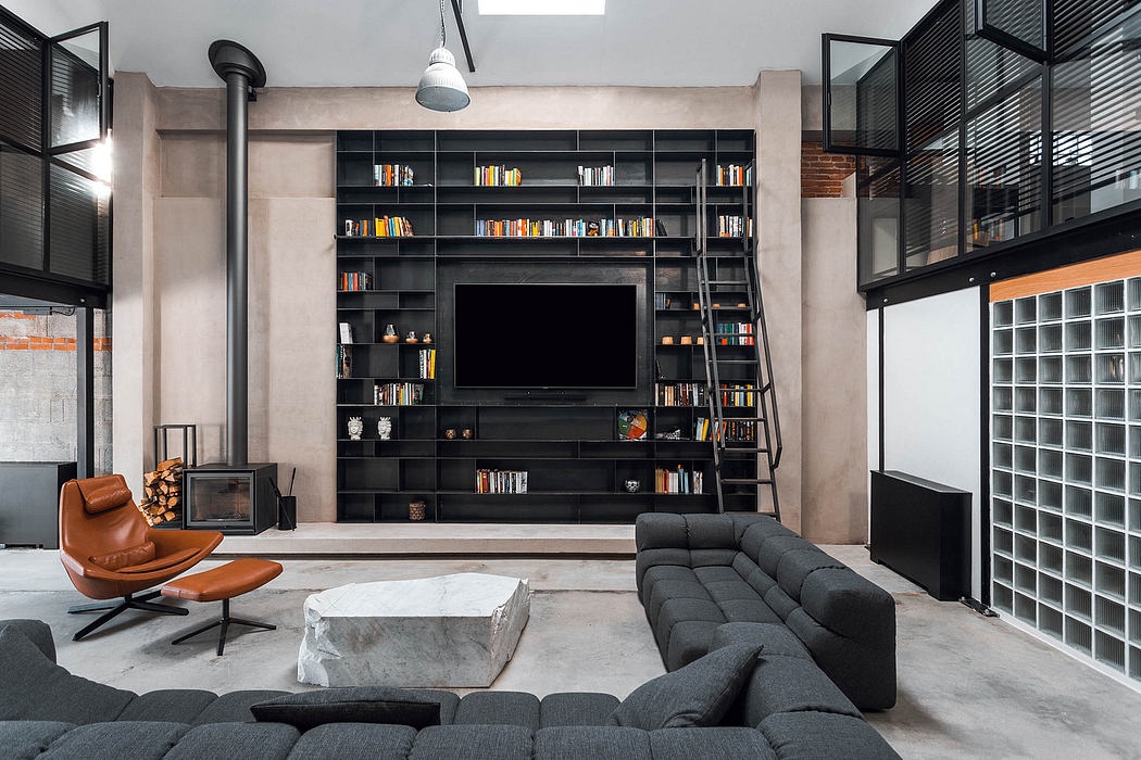 Modern, industrial-style living room with built-in black bookshelves, large TV, and leather chair.