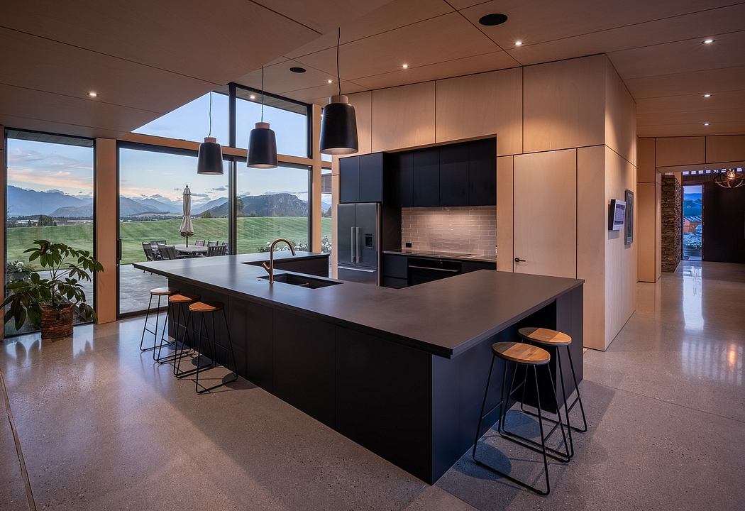 Sleek, contemporary kitchen with black island, pendant lights, and panoramic mountain views.